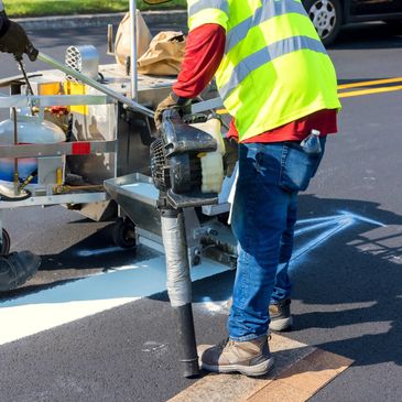 Workers in safety vests painting white lines on a road.