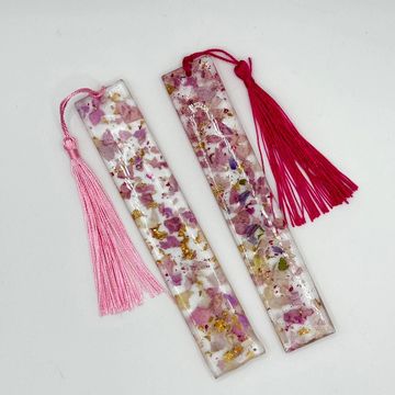 Two delicate resin bookmarks with dried flowers and pink tassels.