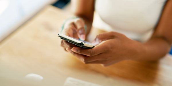 Person using a smartphone with both hands indoors.