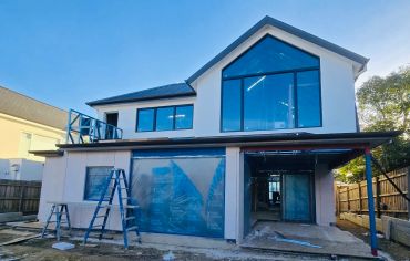 Modern house under construction with large windows.