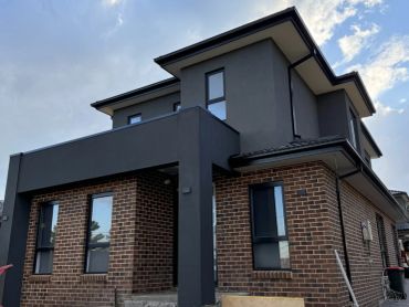 Modern two-story house with brick and dark gray exterior.