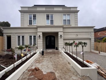 Modern two-story house under construction with landscaping.