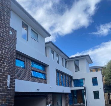 Modern multi-story house under construction with blue windows.