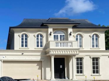 Elegant two-story beige house with balcony and garage.