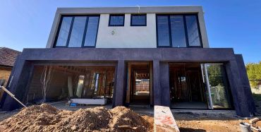 Modern house under construction with large windows.