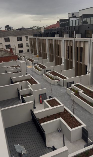 New residential complex with modern townhouses and planters.
