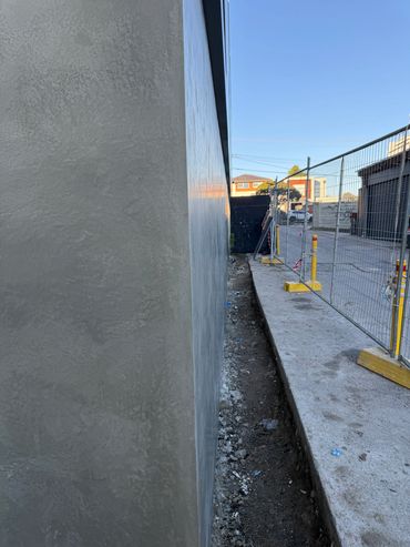 Wet concrete wall next to a construction sidewalk.