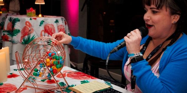Woman calling out bingo numbers with a microphone.