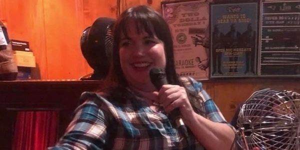 Woman holding microphone, smiling.