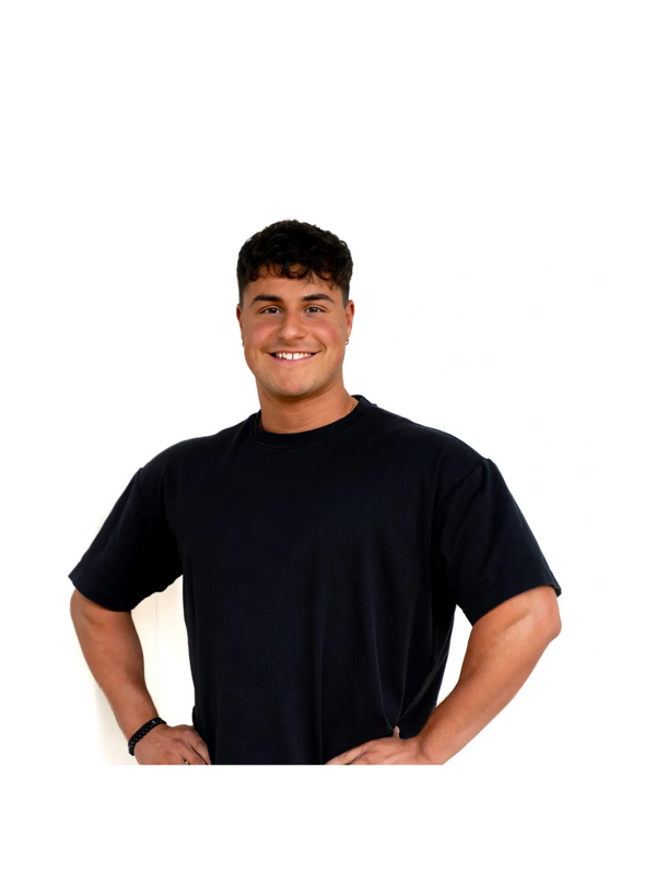 Smiling young man in a black t-shirt poses confidently with hands on hips.