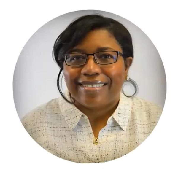 Smiling woman with glasses in a light patterned blouse.