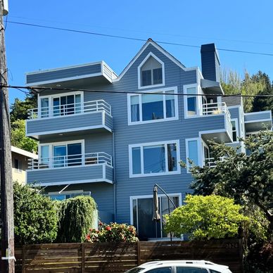 A modern blue three-story house with balconies and large windows.