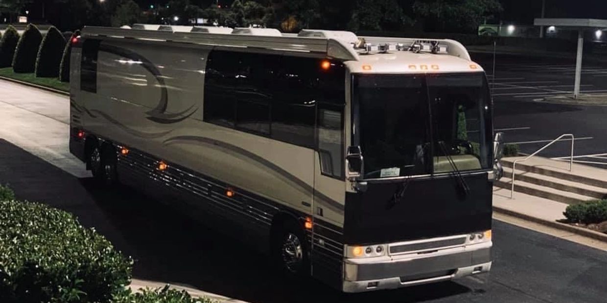A large luxury tour bus parked at night in a dimly lit area.