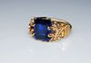 An emerald cut lab grown sapphire is prong set in gold filed wire