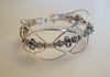 Heavy square sterling silver wires form waves around a center strand of handmade beads from Bali.  