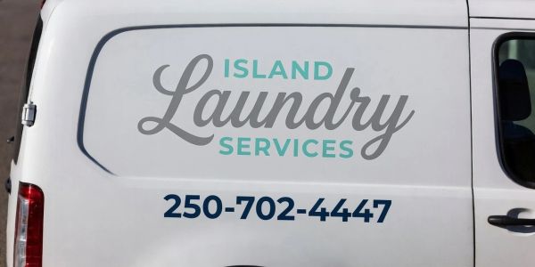 Side of a white van with 'Island Laundry Services' and a phone number.