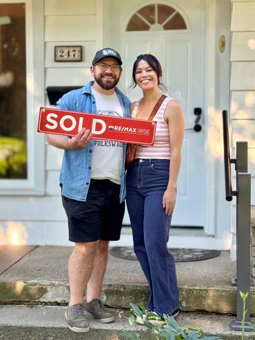 Couple holding something in front of their house
