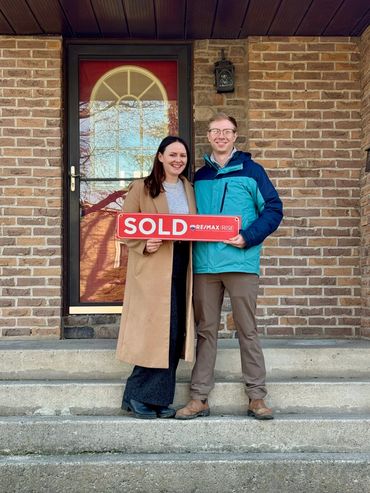 Couple holding something in front of their house