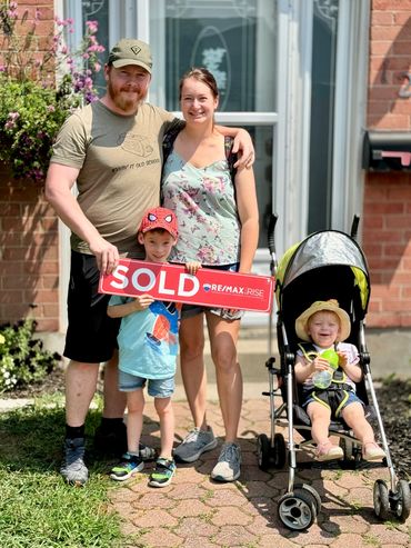 Family holding something in front of their house