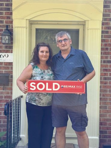 Couple holding something in front of their house