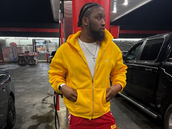 Man in a bright yellow jacket at a gas station at night.