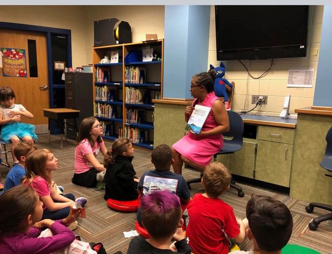 Chloricia Recie) reading her book Inquisitive Island Iguanas to students.