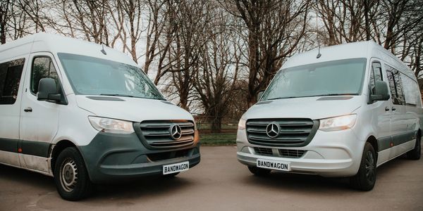 Two white Mercedes vans parked facing each other outdoors.