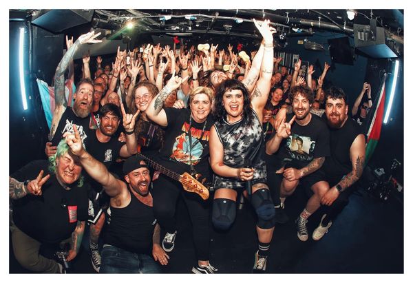 A lively group photo of band members and fans celebrating at a music event.