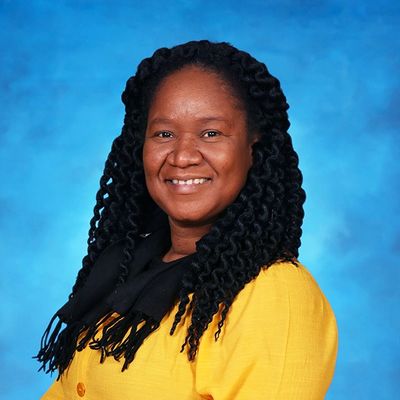 Smiling woman in a yellow jacket with braided hair.