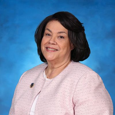 Smiling woman in pink jacket against blue background.