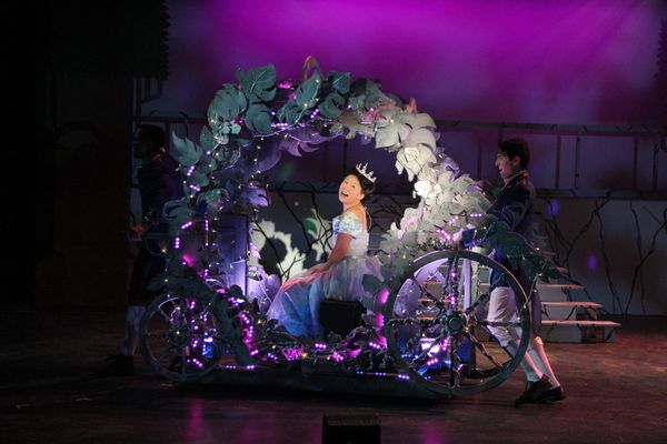 A princess in a glowing carriage during a theatrical performance.