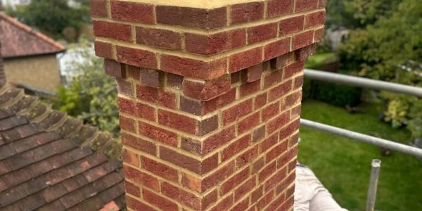 Freshly built brick chimney with two clay pots on top.