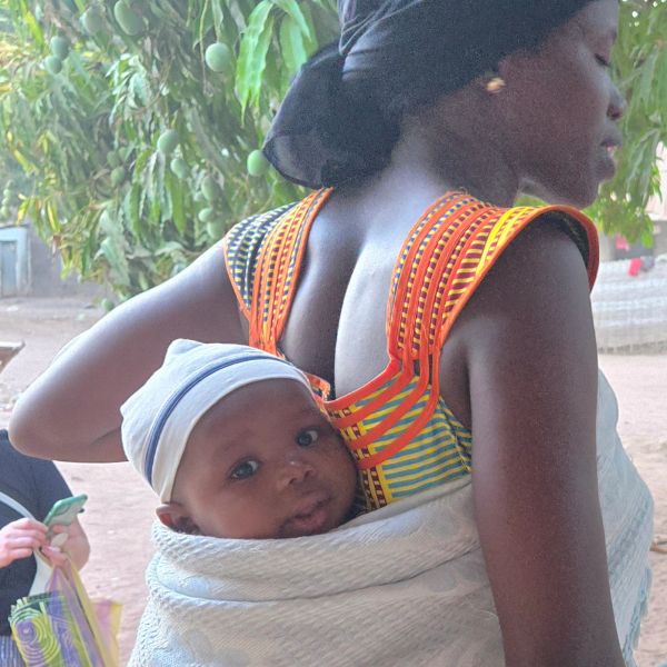 Woman carrying baby on her back with a cloth.