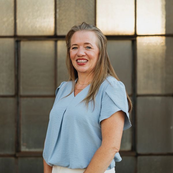Smiling woman in a light blue top with braces.