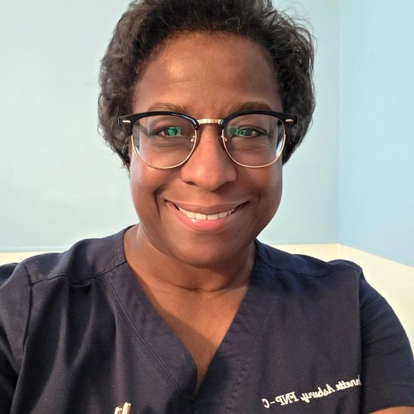 Smiling woman wearing glasses and navy scrubs.
