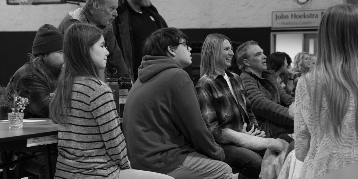 People attentively listening in a community meeting with relaxed, engaged expressions.