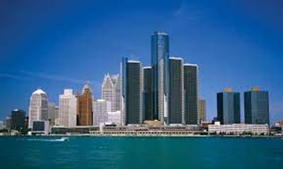 City skyline with tall buildings by the water under a clear blue sky.