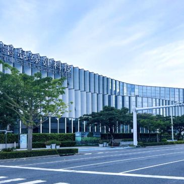 Modern glass building with Chinese signage under a clear blue sky.