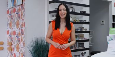 Woman in an orange dress standing in a stylish eyewear store.