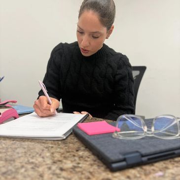 Woman writing at a desk with office supplies.