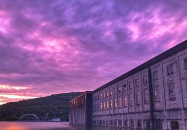 Purple sunset sky over river and building.