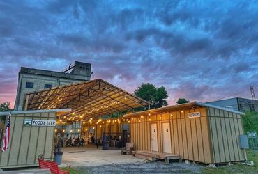 Outdoor food and beer venue at dusk with vibrant sky.