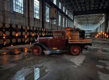 Vintage truck inside a warehouse with barrels.
