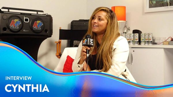 Woman named Cynthia being interviewed with a microphone indoors.
