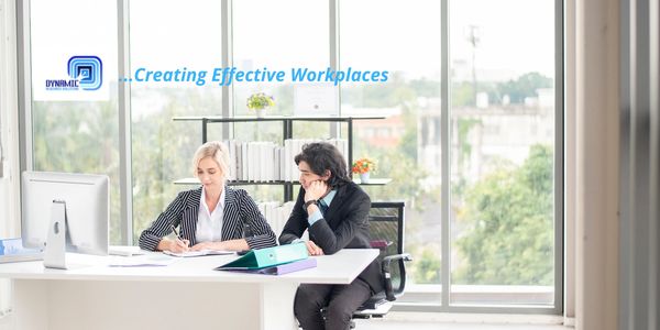 Two professionals collaborating in a bright modern office with city views.