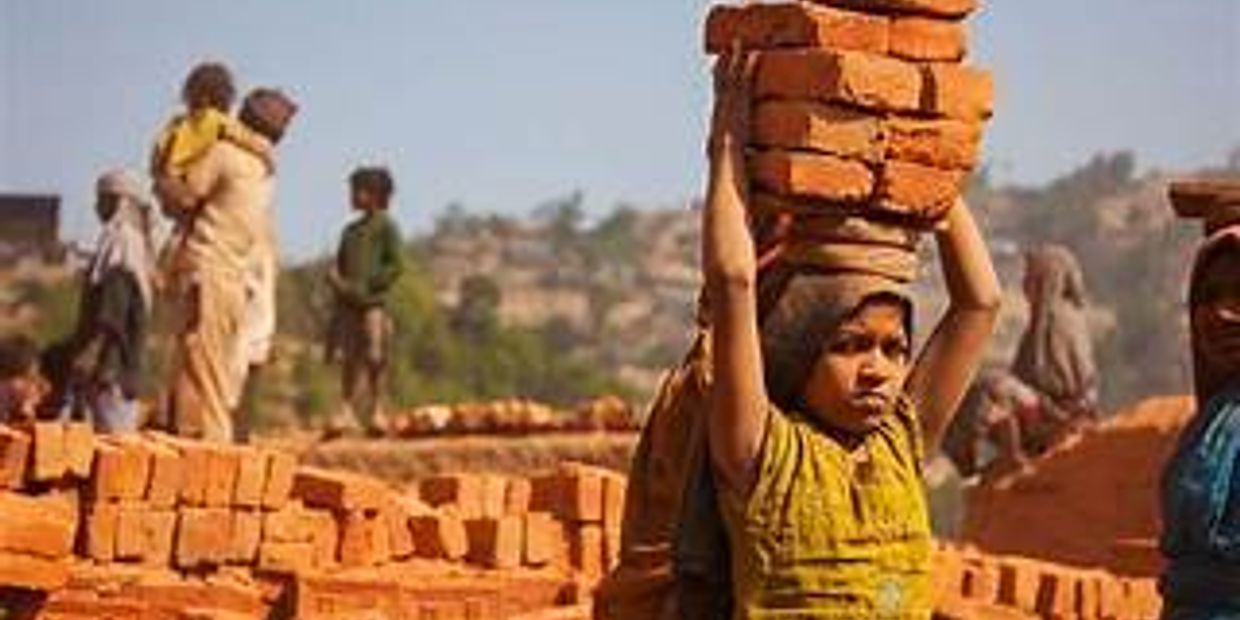Young child carrying bricks on her head in a brick kiln.