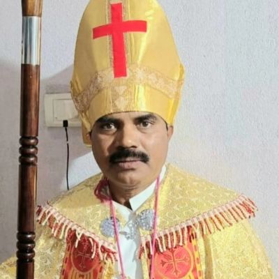 Man dressed as a bishop in gold robes and a mitre with a red cross.