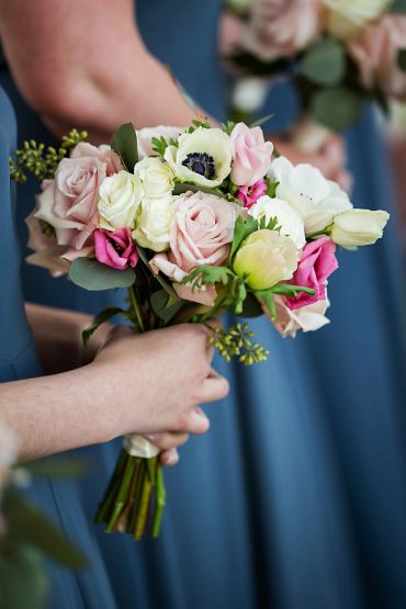 Hand holding a bouquet of roses and other flowers.