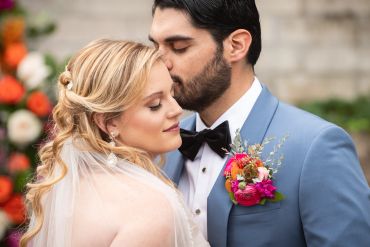 Groom kissing bride's forehead at wedding.
