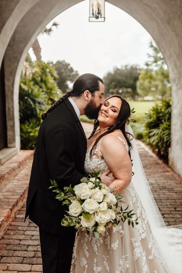 just married couple Groom in black tux and bride holding white floral bouquet